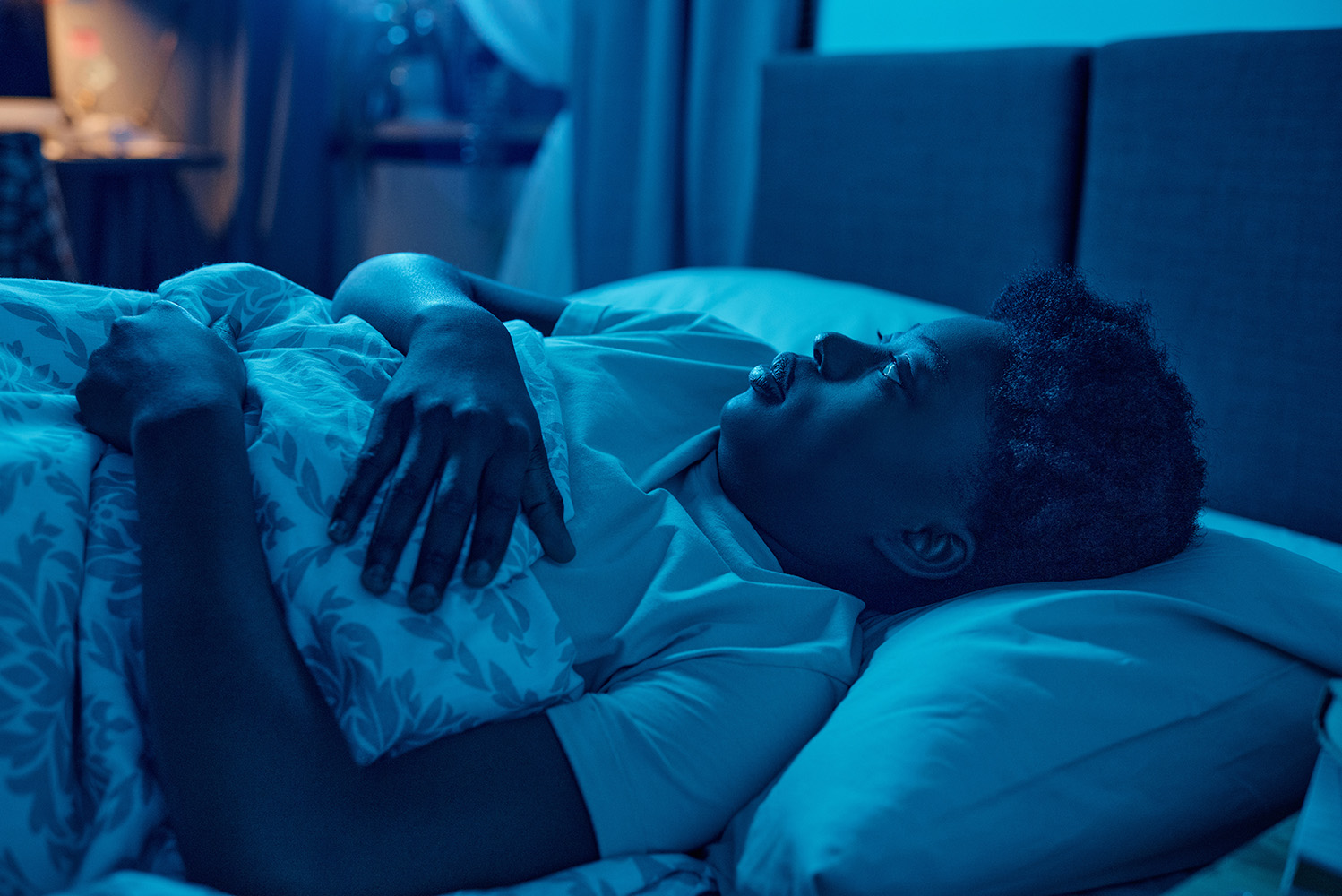 Woman lying awake in bed, trying to sleep.