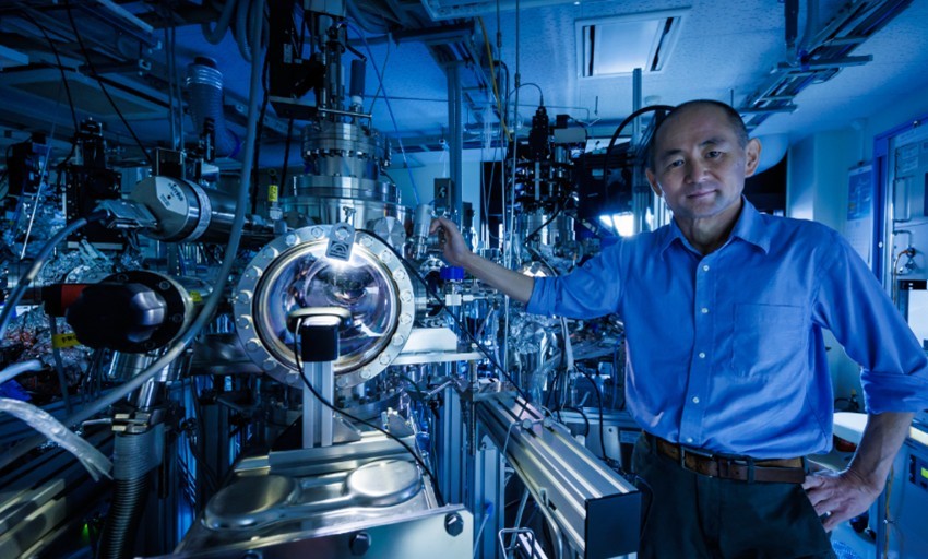 Photo of  Professor Taro Hitosugi standing beside his team's autonomous experiment system.