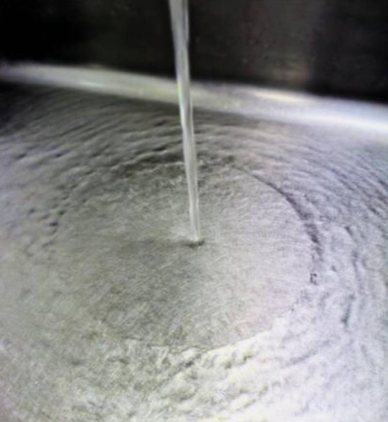 Photo of water running out of a tap into a metal kitchen sink.